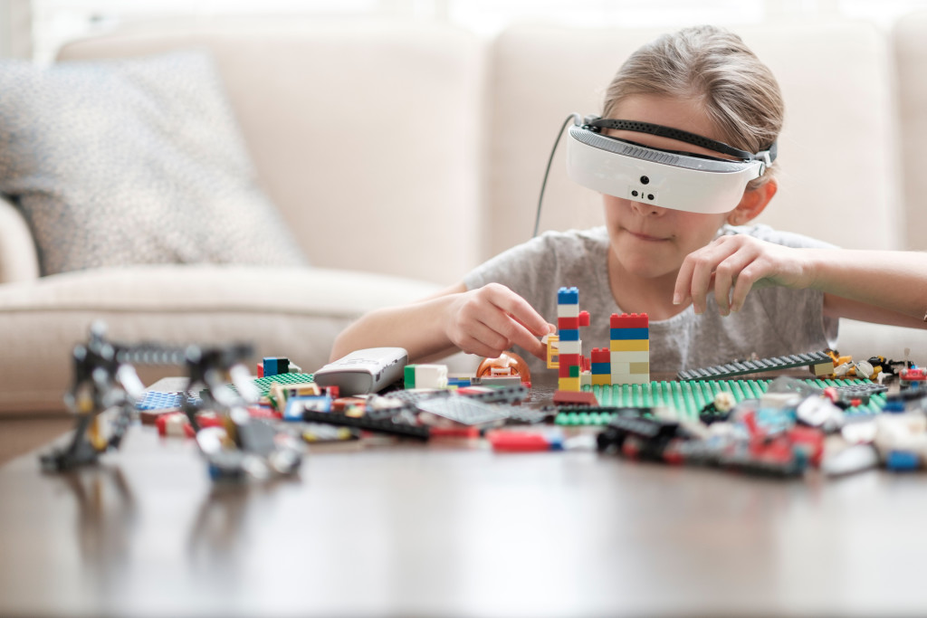 eSight- Glass. In this picture, A visually impaired children wear the eSight and arrange the toy color bricks with help of eSight glass.